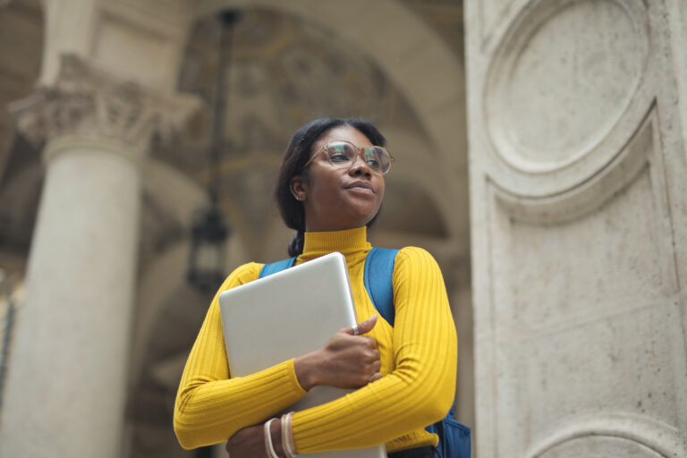 young black woman wearing glasses with a laptop at university.